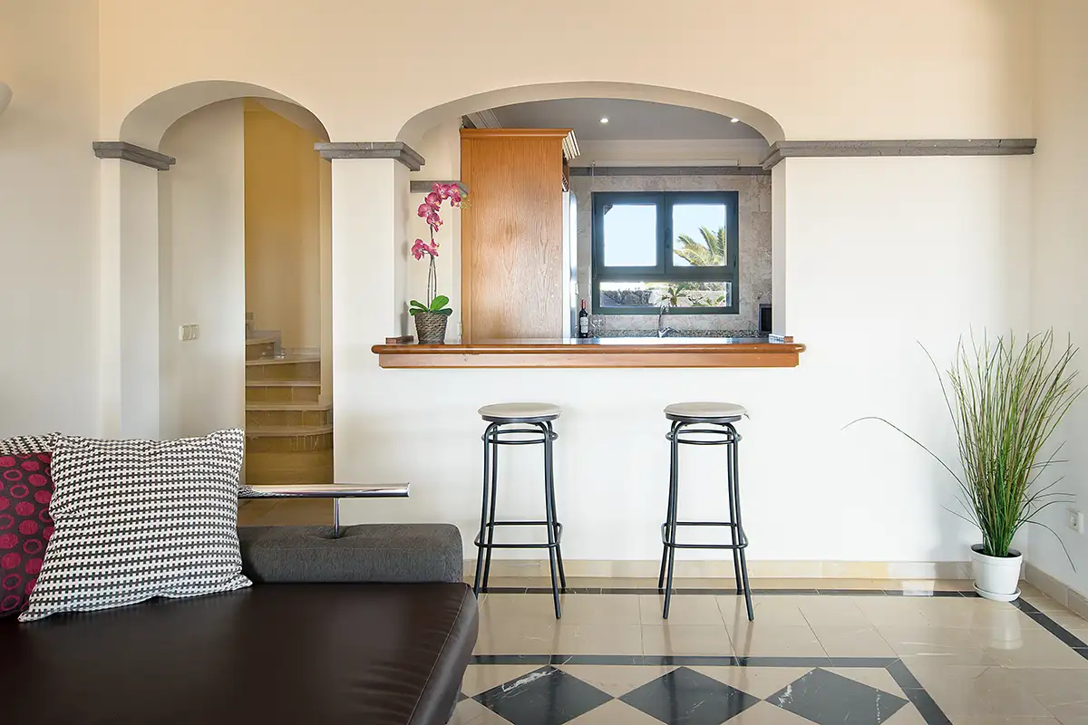 Salón con ventana office de la cocina de la Villa Hipoclub 