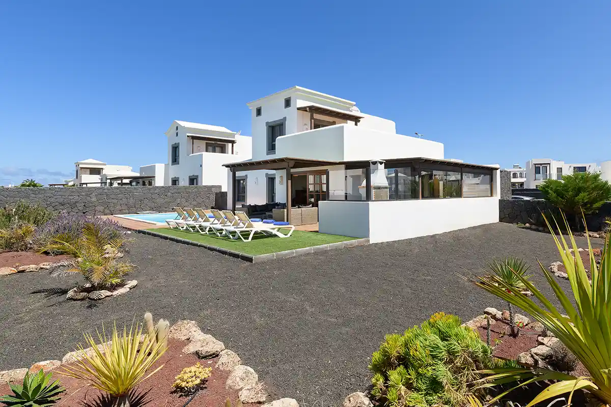 Jardines de gran extensión con recubrimiento de piedra volcánica rodeando la villa en Hipoclub Villa Aguamarina 30