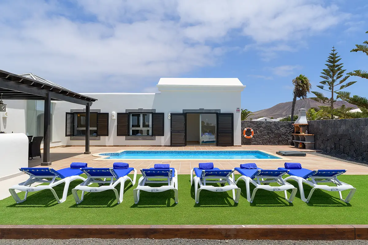 Sun loungers on the lawn next to the pool at Villa Faro Park 189 Hipoclub