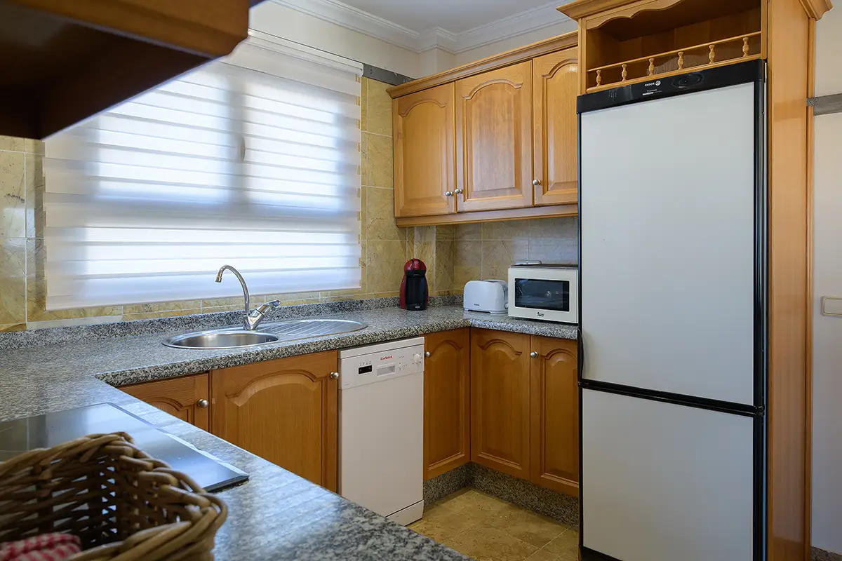 Cocina interior equipada con mobiliario y electrodomésticos incorporados en Hipoclub Villa Aguamarina 4