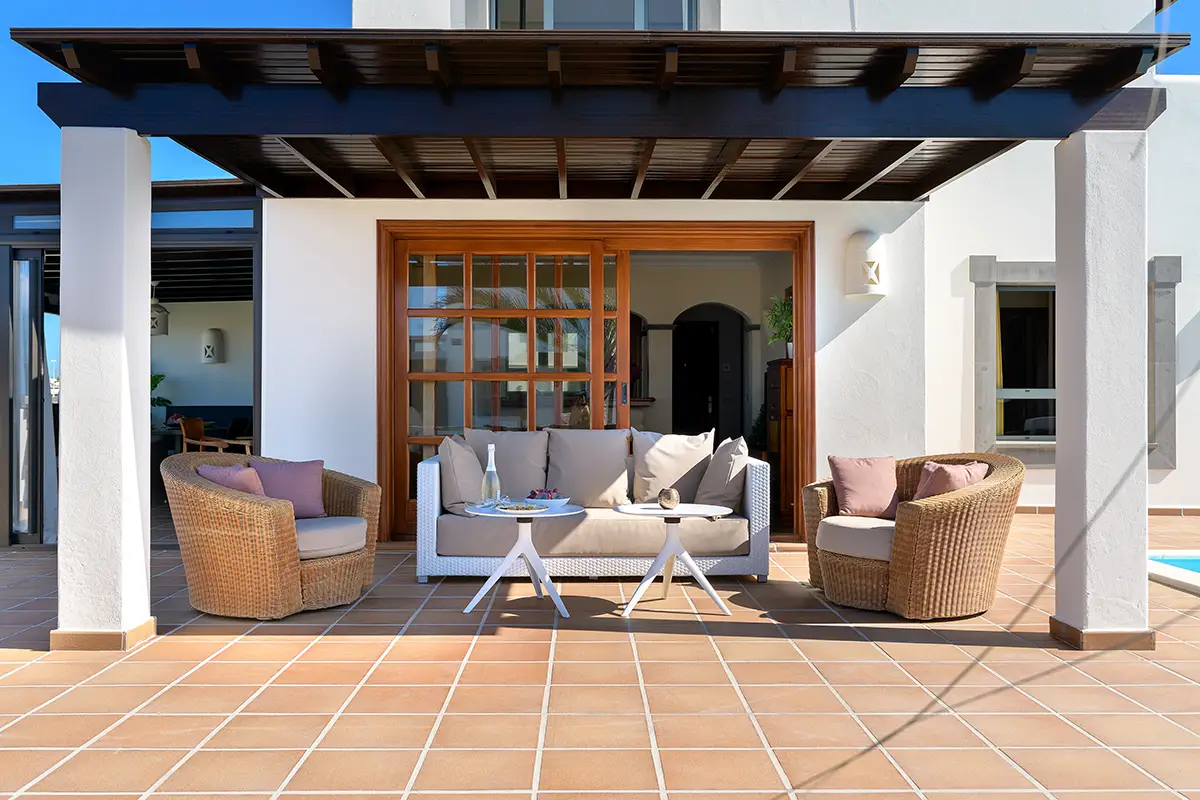 Covered terrace with comfortable armchairs and side table at Hipoclub Villa Aguamarina 1