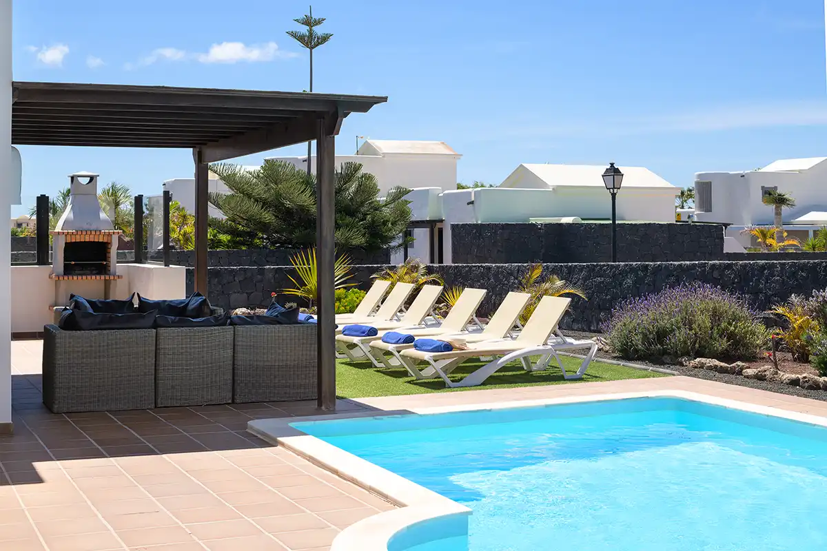 Vista parcial del área de piscina con zona de hamacas y pérgola de madera equipada con sillones de exterior en Hipoclub Villa Aguamarina 30