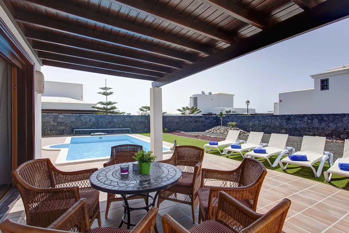Terraza situada bajo pérgola con mobiliario de jardín en Hipoclub Villa Aguamarina 4