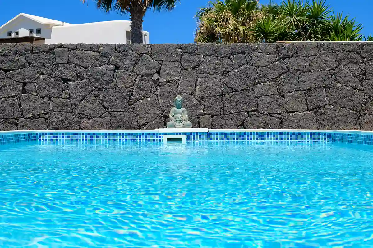 Vista del muro de piedra volcánica desde la piscina en Hipoclub Villa Zafiro 54